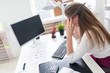 © Ivan Traimak - A young girl sitting at a computer table and holding hands on his head.
