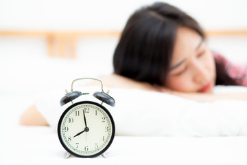 closeup alarm clock and beautiful asian young woman in morning, wake up for sleep with alarm clock, relax and lifestyle concept.