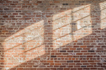 OLD RED / ORANGE RUSTIC BRICK WALL WITH SHADOW OF WINDOWS AND NATURAL LIGHT