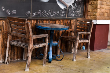 Two wooden chairs and wooden desk near the wall at front coffee shop.