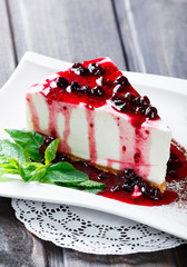 Wall Mural - Dessert Cheesecake with Berries Sauce and green mint in plate on dark background