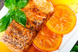 Honey Glazed fillet salmon with orange slices, spices and basil on white plate on dark background. Delicious dish of seafood.