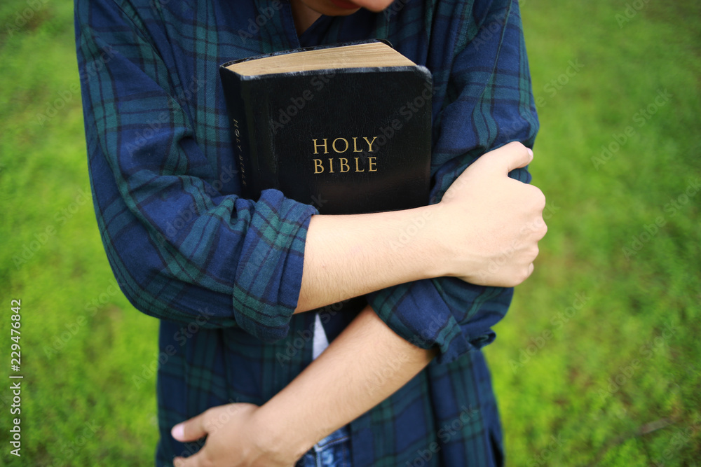 Scripture Hug A woman is holding and hug the bible in the morning. Hands folded in ...