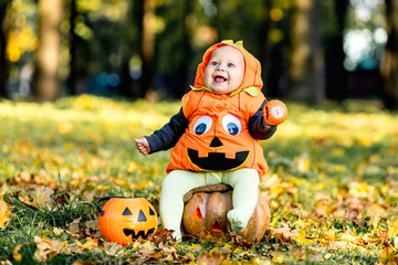 Child in pumpkin suit on background of autumn leaves