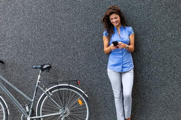 Wall Mural - Portrait of businesswoman with her bicycle looking at mobile phone.