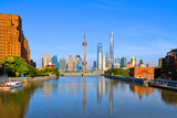 Fototapeta Nowy Jork - historical Waibaidu bridge with water reflections and colorful blue sky in front of the futuristic modern skyline of Pudong Shanghai, China
