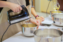 Asian Woman Hand Is Holding A Bowl And Egg Beater Flour Mixer On White Table.