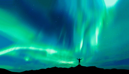 aurora borealis with silhouette standing man on the mountain.freedom traveller journey concept