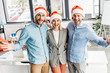 © LIGHTFIELD STUDIOS - cheerful young business team in santa hats smiling at camera in office