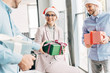 © LIGHTFIELD STUDIOS - smiling young coworkers presenting christmas gifts in office