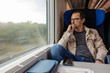 © dtatiana - Middle age man looking out of the window of train. Passenger during travel by high speed express train in Europe