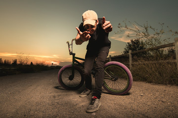 Wall Mural - Portrait of a young man with a bmx bicycle. Guy riding a bike in a sunset