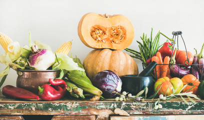 Fall vegetarian food ingredient variety. Assortment of various Autumn vegetables for healthy cooking over wooden rustic cupboard, white wall background. Local market organic produce