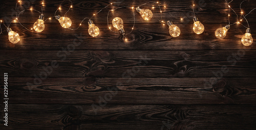 Foto Empty, dark wooden background illuminated by retro light bulbs, with copy space