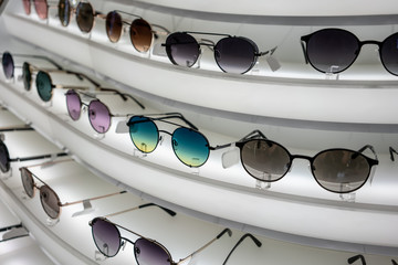 Various of sun glasses in the shop curve display shelves.