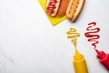 Top View Of Delicious Hot Dogs With Mustard And Ketchup On White Marble Surface