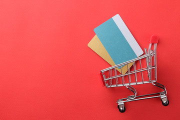 The concept of online shopping. Composition with discount cards and shopping trolley on a red background