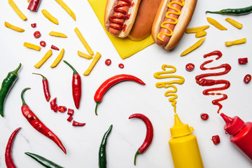 Wall Mural - top view of delicious hot dogs, peppers and fries with mustard and ketchup on white surface