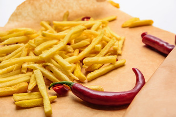 Wall Mural - tasty french fries with spicy peppers on parchment paper on white