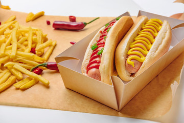 Canvas Print - close-up shot of spicy hot dogs with french fries on parchment paper