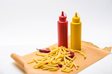 Wall Mural - close-up shot of delicious french fries with pepper, ketchup and mustard on white