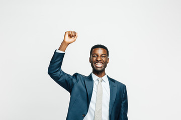 Wall Mural - Portrait of a happy young man in business suit with fist  up, isolated on white studio background