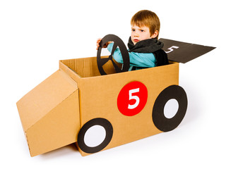 Young boy driving his cardboard car