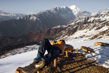 Wall Mural - Young traveler wear orange sweater sleeping on the old wooden chair at Himalaya mountains.