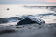 Stein am Strand mit Wellen