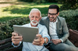 © bnenin - Two elegant men taking selfie on a tablet outdoors.
