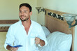 © Антон Зимин - happy young handsome bearded man in white clothes enjoying his morning with cup of coffee or water smiling. Bachelor holding a glass of water, sitting on a bed, he is a freelancer