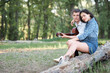 © soleg - young couple sitting on a log in the forest and playing guitar, summer nature, romantic feelings
