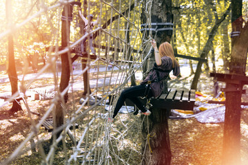 happy girl, selective focus, climbing gear in an adventure park are engaged in rock climbing rope road, arboretum, insurance, attraction, amusement park, active recreation, autmn