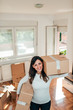 © bnenin - Young woman carrying cardboard boxes for moving into new home.