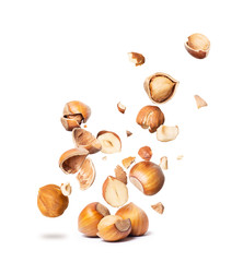 Poster - Сracked hazelnuts fall down isolated on white background