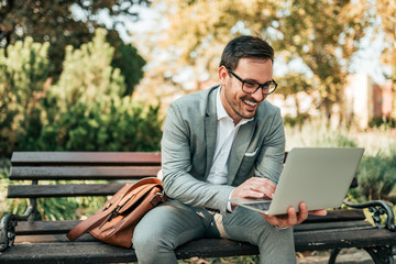 Handsome businessman using laptop in the park.