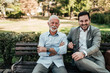 © bnenin - Portrait of a business family outdoors. Two men sitting in the park looking at camera.