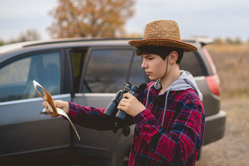 young man in hat with road map and binoculars searching the correct road  f