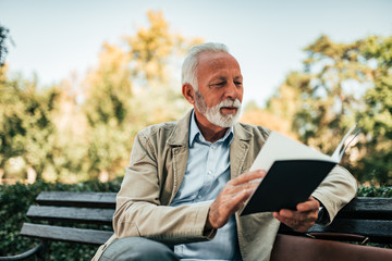 Charming old man reading a book.