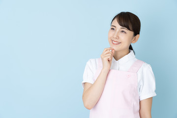 Poster - portrait of young asian nurse wearing apron on blue background