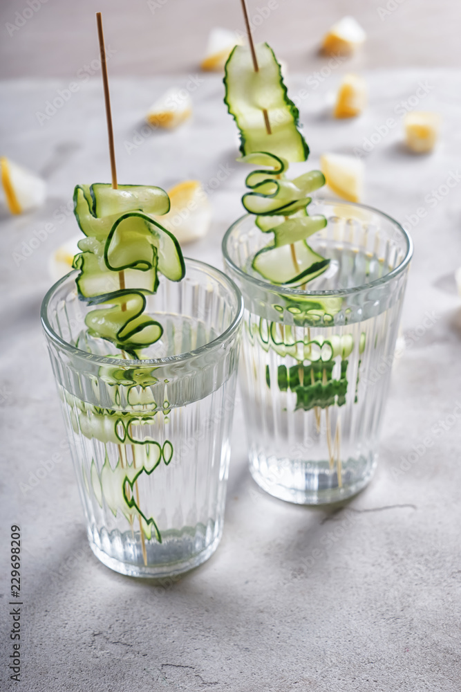 Glasses of fresh cucumber water on grey table