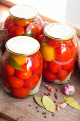 Glass jars with red pickled tomatoes, sealed with metal lid