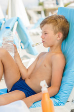 Sad Little Boy On Hot Beach With Sunstroke Measures The Temperature And Holds A Bottle Of Water