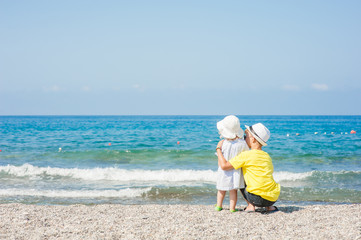 Young boy hugging baby girl on the beach on summer holidays. concept of summer family vacation. Empty space for text