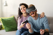 © NDABCREATIVITY - Happy young couple playing video games with virtual reality headsets
