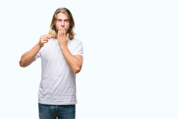 Sticker - Young handsome man with long hair eating chocolate cooky over isolated background cover mouth with hand shocked with shame for mistake, expression of fear, scared in silence, secret concept