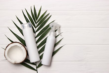 Tropical Leaf, Care Cosmetics And Coconut On A Wooden Table. Top View. Means For Hair, Body, Skin. Flatlay