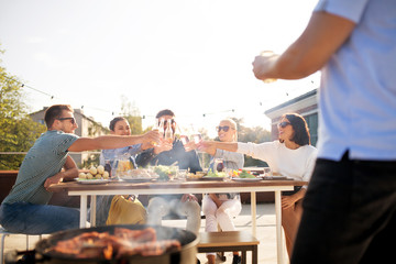 Canvas Print - leisure and people concept - happy friends toasting drinks at barbecue party on rooftop in summer