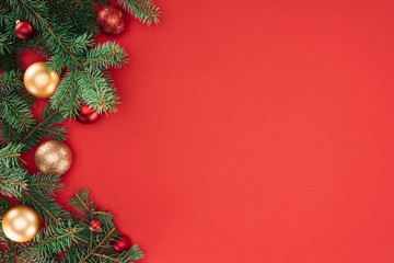 Wall Mural - flat lay with pine tree branches with red and golden christmas balls isolated on red