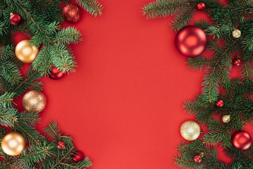 flat lay with pine tree branches with red and golden christmas balls isolated on red